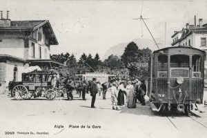 1900 – En gare d’Aigle, seule la ligne AL existe, avec le tram pour le Grand Hôtel à l’arrière-plan. Une diligence assure les relations ASD-AOMC. © Collection G. Hadorn